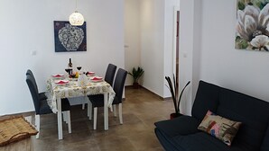 A dining area with a table set for four, chairs, a hanging light fixture, and wall art. - Nice house with large solarium in Cordoba (Córdoba)