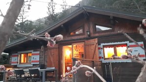 Uma cabana de madeira com área de jantar e luz interior aconchegante.