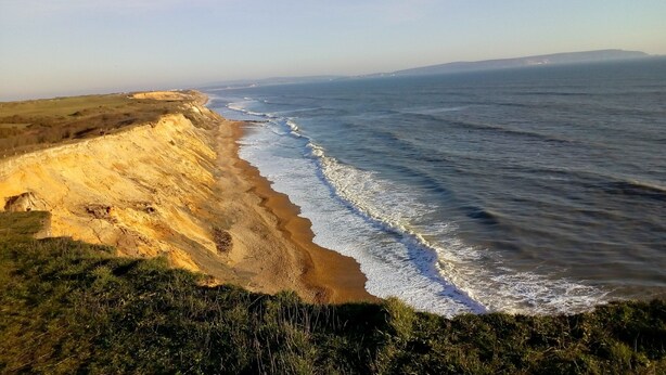 Un paisaje costero con una playa arenosa y acantilados.