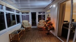 Una sala de estar acogedora con suelo de madera, dos sillones, una mesita y un árbol de Navidad.