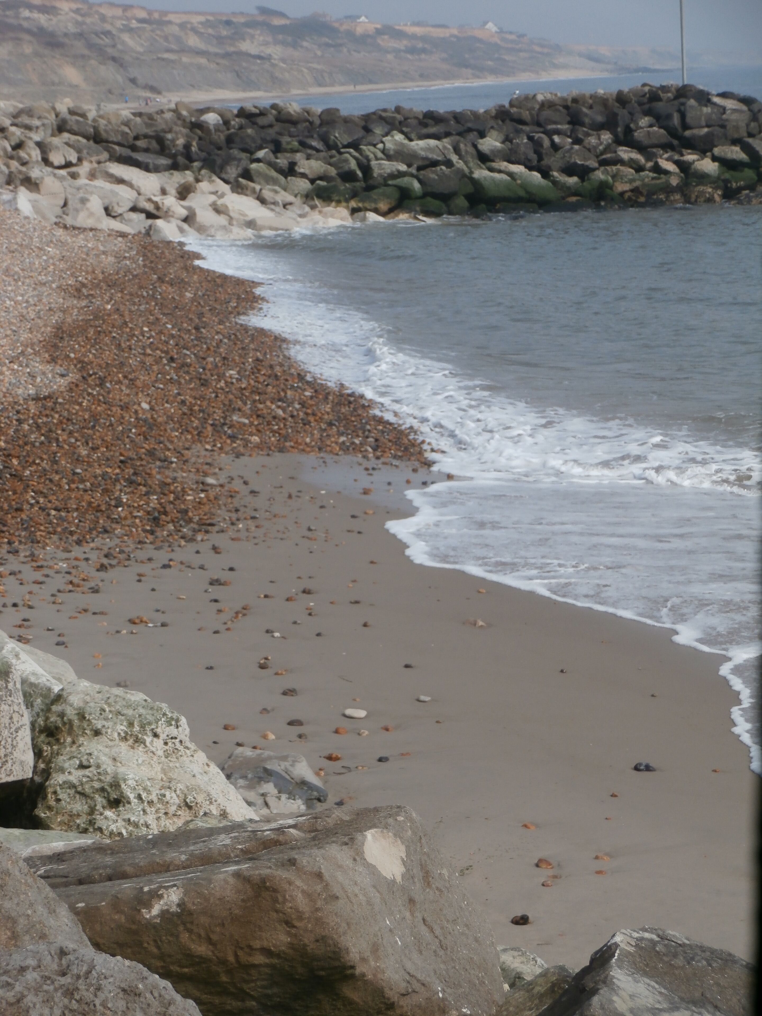 Una playa rocosa con piedras y un muro de piedra.