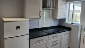 Una cocina con armarios blancos, encimera negra y estufa integrada.