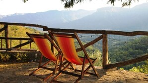 Two wooden chairs with a red and yellow striped cushion, positioned on a stone platform with a view of a mountainous landscape. - Barga -cottage & barn 6 hctres of land, private pool, WIFI , stunning views! (Barga)