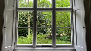 A room with a large window featuring six panes, offering a view of lush greenery outside. - 10-16 persons. Variable rates. 4 large (20-25 sq mtr) en suite rooms. (Colerne)