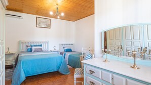A bedroom with two beds, a dresser, a mirror, and a chandelier.