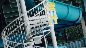 Un escalier en colimaçon avec une rampe métallique menant à un toboggan bleu.