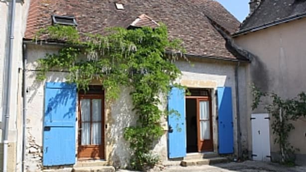 Il s’agit d’un bâtiment traditionnel, doté d’un toit recouvert de tuiles, de deux portes bleues et d’un petit jardin.