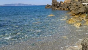 A clear coastal view with rocky formations and calm sea.