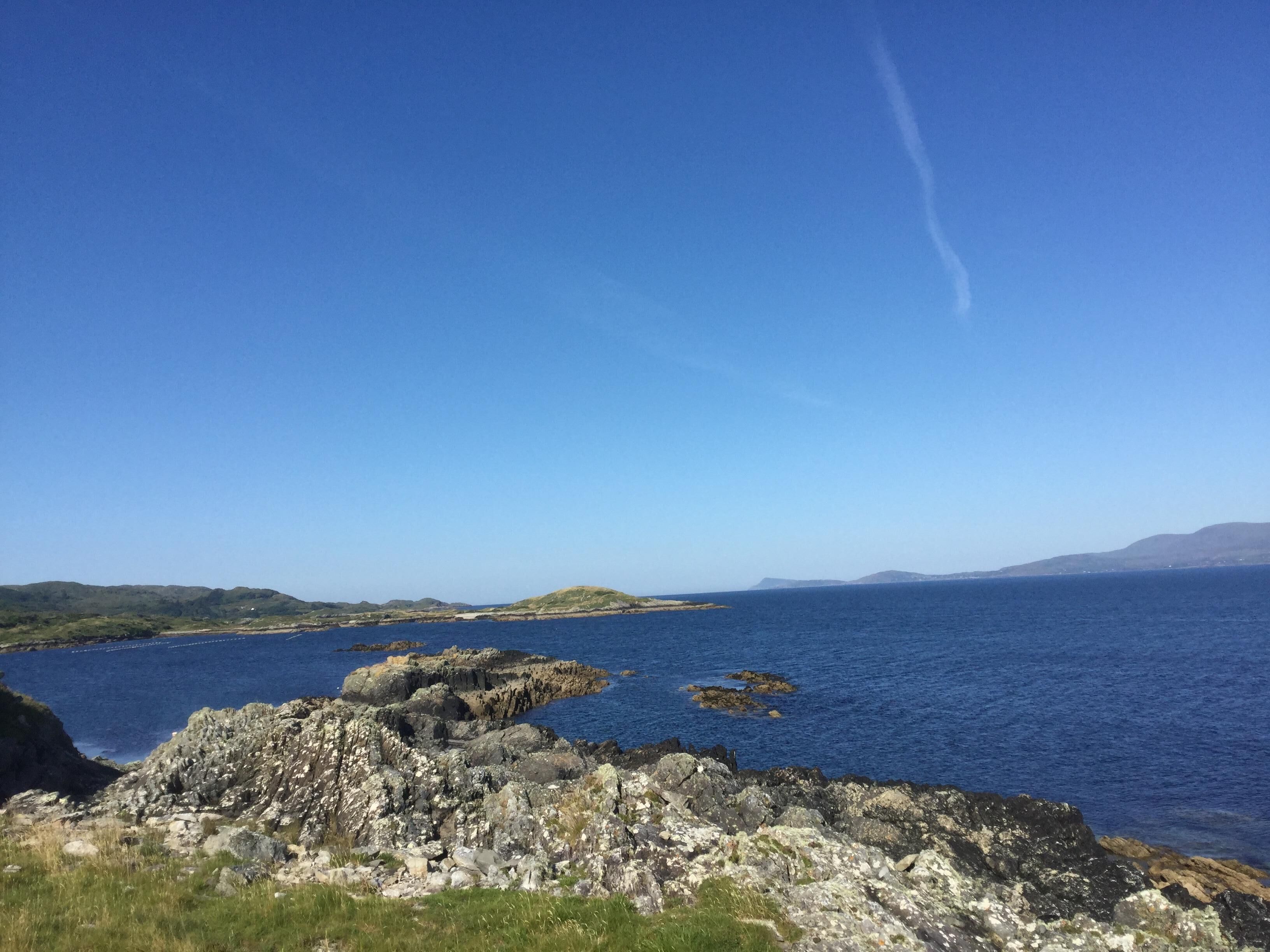 A coastal landscape with rocky terrain and a clear blue sky.