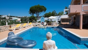 Ein Swimmingpool mit Liegestühlen und einer Buddha-Statue.