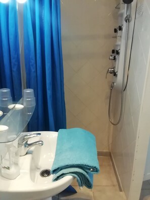 Een bad/douchecombinatie, een haardroger, handdoeken, toiletpapier