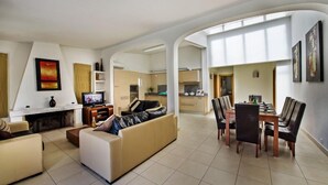 Un amplio salón con sofá, televisión y mesa de comedor.