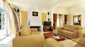 Una sala de estar con sofás color beige, un televisor de pantalla plana y una chimenea.