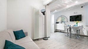 Una sala de estar moderna con un sofá, una lámpara de pie y una zona de cocina con una mesa de comedor y sillas.