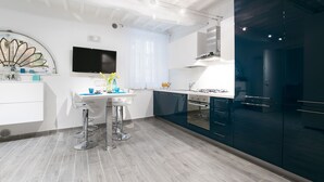 Una cocina moderna con encimera blanca, armarios oscuros y horno empotrado.