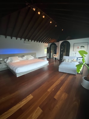Une chambre avec un plancher en bois, un lit, une chaise et un bureau.