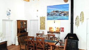 A dining area with wooden furniture, a black stove, and a cityscape painting on the wall. - 🔑🔑🔑🔑Villa Can Mestreso New Suite Ibiza ETV1227E👍👍👍👍👍👍 (Ibiza)