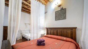 A bedroom with a wooden headboard, a bed with an orange bedspread, a white bedside table, and a wooden nightstand. - 🔑🔑🔑🔑Villa Can Mestreso New Suite Ibiza ETV1227E👍👍👍👍👍👍 (Ibiza)