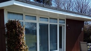 Et moderne hus med stor glasdør, en lille have og en terrasse.