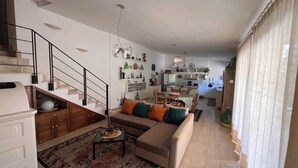 Ein modernes Wohnzimmer mit einem beigefarbenen Sofa, einem Couchtisch und einer Treppe mit schwarzen Geländern.
