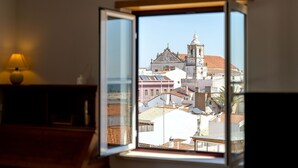 A room with a window overlooking a historic building with a bell tower.