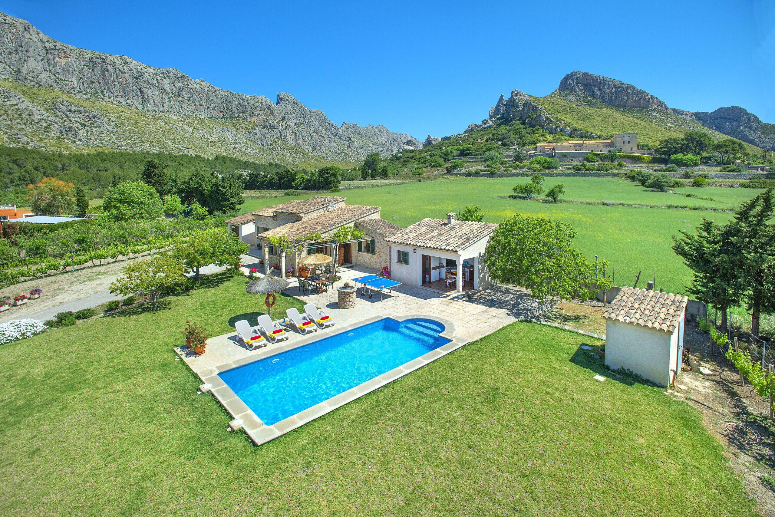 A residential property with a swimming pool, a patio area with lounge chairs, and a view of the surrounding landscape including mountains.