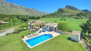 Il s’agit d’une propriété résidentielle dotée d’une piscine, d’un patio aménagé avec des chaises longues et offrant une vue sur le paysage environnant, notamment les montagnes.