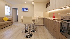 Eine moderne Küche mit Essbereich, Holzschränken und einem an der Wand befestigten Fernseher.