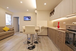 A modern kitchen with a dining area, wooden cabinets, and a TV mounted on the wall. - BELLAGIO NEAR THE LAKE, A STYLISH APARTMENT, GARDEN, PARKING RELAXING POSITION (Bellagio)