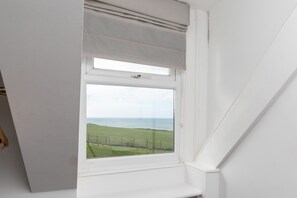 A window with a view of a grassy field and a body of water. - Stunning seaside with cinema room, sea views  - ideal for friends and families (Newquay)