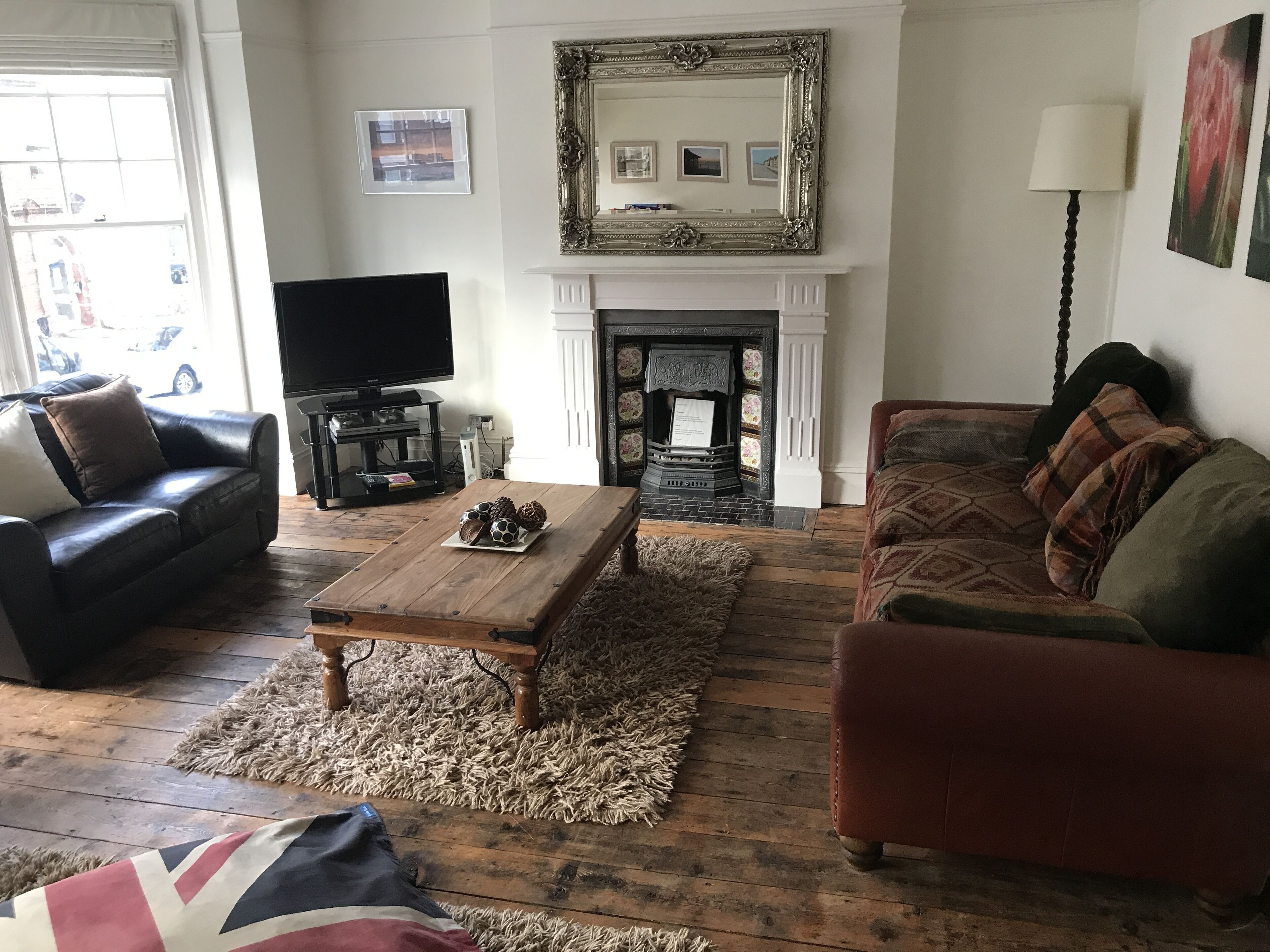 Una sala de estar con chimenea, sofás de cuero, una mesa de centro y un televisor.