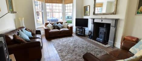 A living room with a fireplace, leather sofas, and a large mirror.
