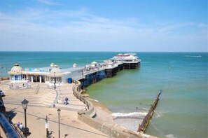 A pier extending into the sea with a viewing platform and a building with a dome structure.