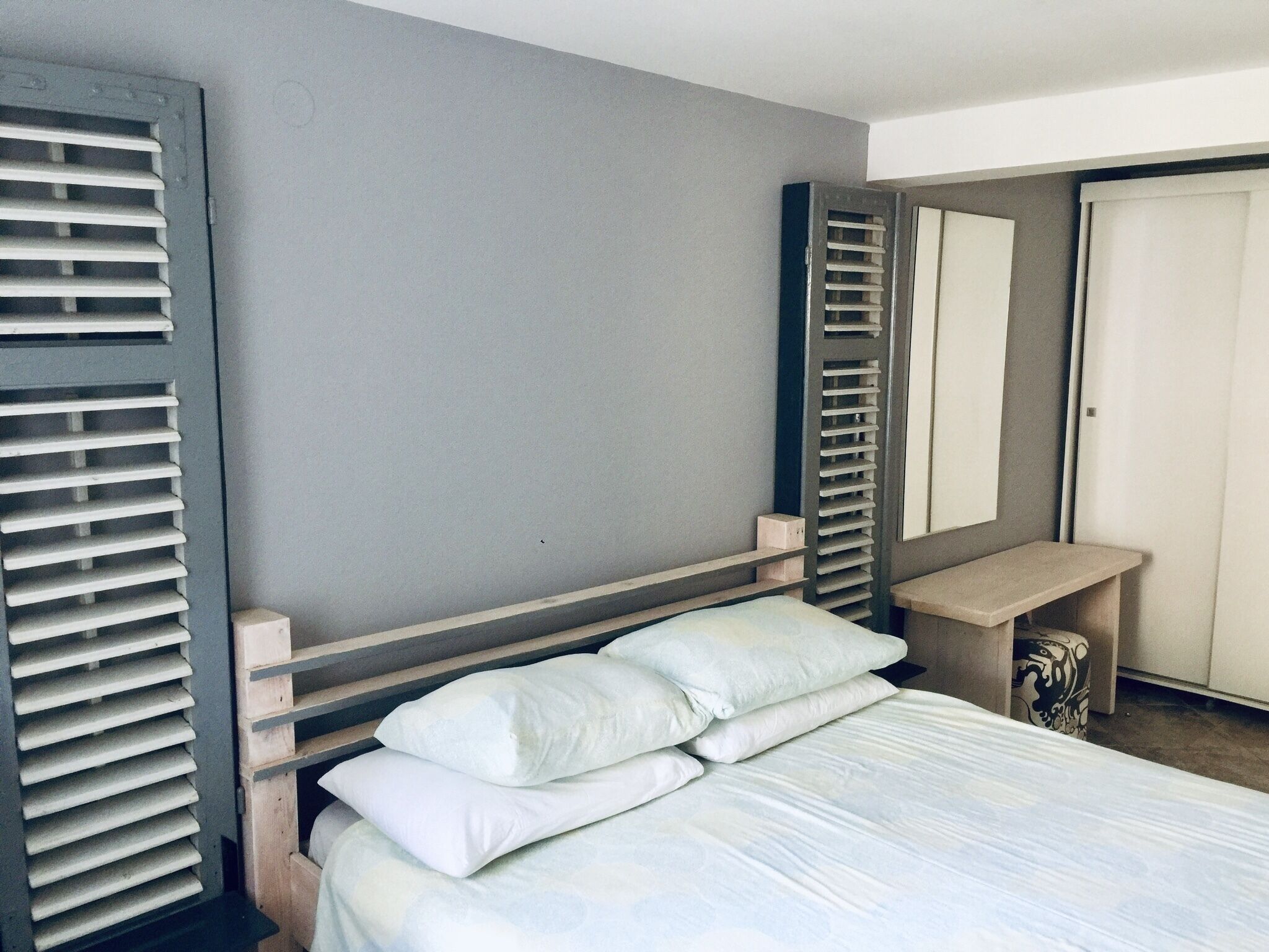 A bedroom with a bed, a bedside table, a mirror, and a wardrobe.