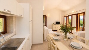 A compact kitchen with a sink, cabinets, and a dining area with a table set for two.