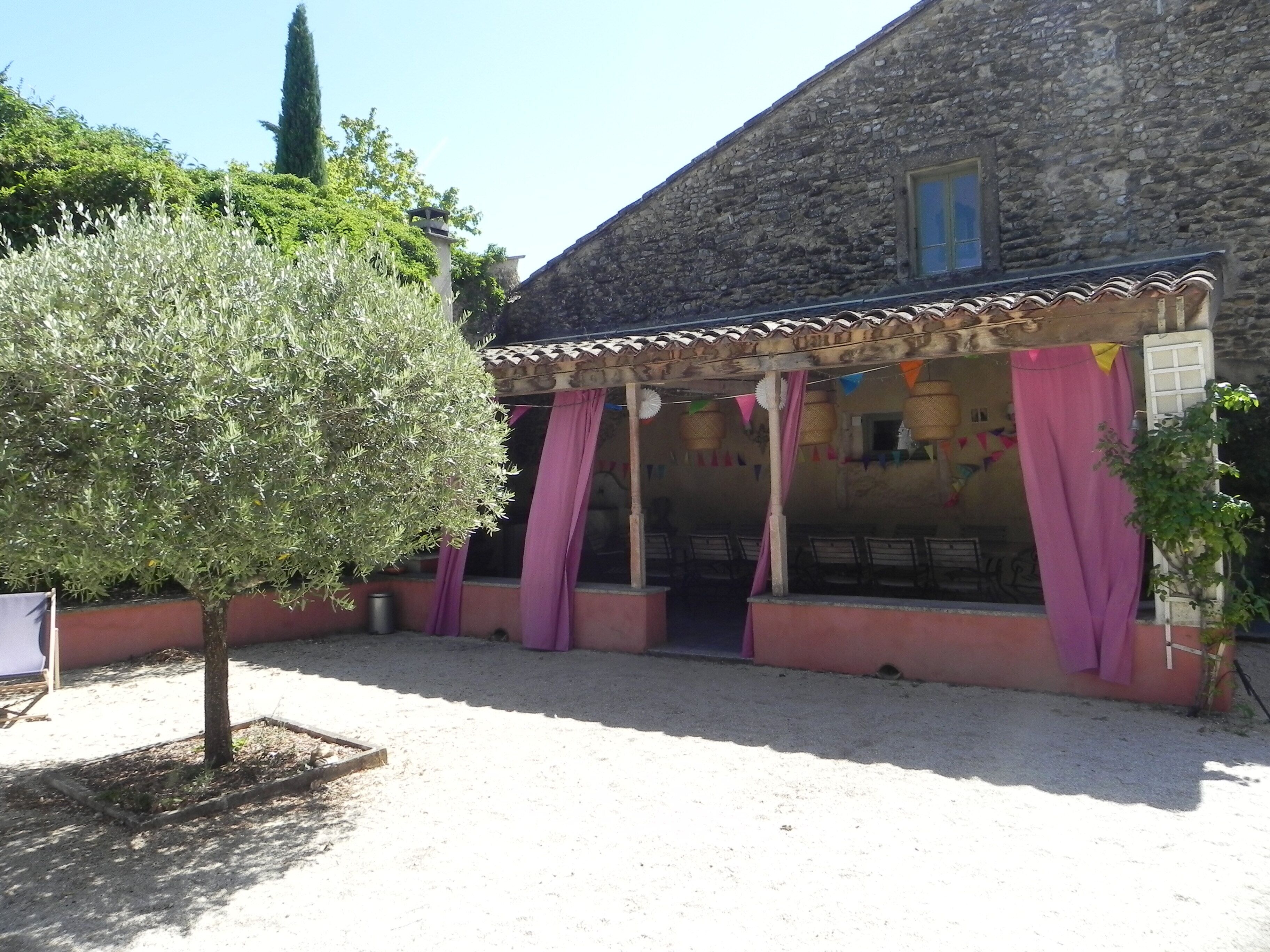 A stone building with a covered patio area, a tree, and a window.