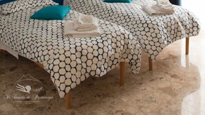 Uma cama de casal com roupa de cama estampada, uma cabeceira e uma mesa de cabeceira com abajur.