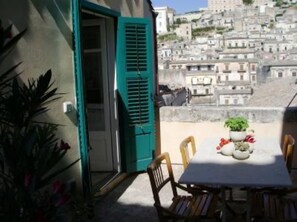 A terrace with a table and chairs, overlooking a densely packed hillside of buildings. - Vico Muccio - historical house, finely restructured with a splendid view on the historical Baroque city of Modica (Modica)