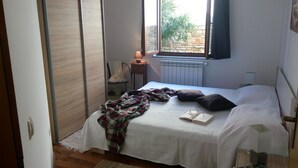 Une chambre à coucher avec un lit, une chaise, une fenêtre et un radiateur.
