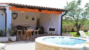 Un espace extérieur abrité comprenant un jacuzzi, des sièges et des plantes en pot.