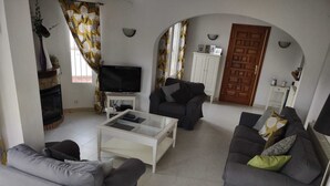 Una sala de estar con chimenea, televisor y dos sofás.