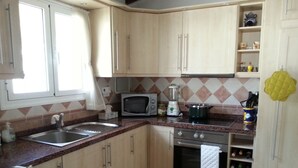 Una cocina compacta con lavamanos, microondas, estufa y espacio para vinos.