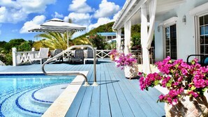 A pool area with lounge chairs, a pergola, and potted flowers.