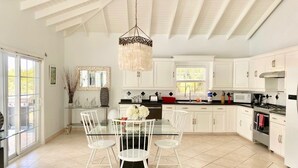 A modern kitchen with white cabinetry, a dining table with chairs, and a chandelier.