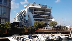 Un immeuble à plusieurs étages doté de balcons, une marina avec des bateaux et une enseigne de casino.