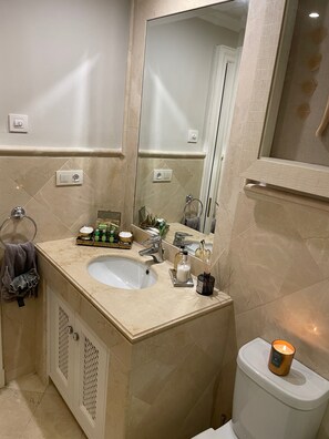 A bathroom with a sink, mirror, toilet, and towel rack.