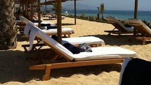 Une plage avec des chaises longues et des parasols en chaume.