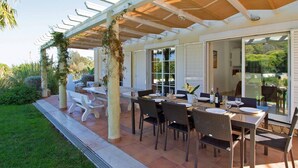 An outdoor patio with a covered dining area, white furniture, and a view of the garden. -  Beautiful 5 bed detached villa, private pool, 700m from the beach - 66875/AL (Castro Marim Praia)