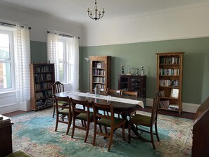 A dining room with a table set for six, surrounded by chairs, and flanked by two wooden bookshelves filled with books. - Extended Victorian Manor House With Conservatory / large Garden, sleeps 10 (Cardross)
