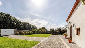 Een geplaveid binnenhof met een gazon, een stenen pad en een wit gebouw met een rood dak.